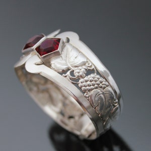 Puede incluir: Pulsera de plata con dise&ntilde;o de vid y dos piedras preciosas rojas.