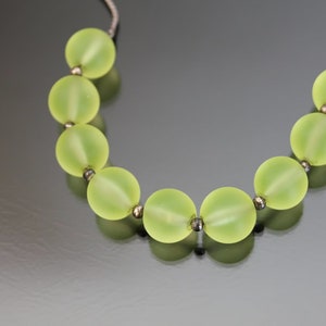 May include: A necklace made of light green glass beads with silver accents.