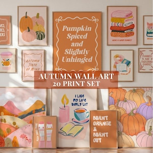Op de afbeelding: Een set van twintig muurkunstprints met herfstthema's, waaronder pompoenen, knusse dekens, boeken, kaarsen en tekstontwerpen in tinten oranje, roze en crème, gepresenteerd in een galerijwandopstelling.