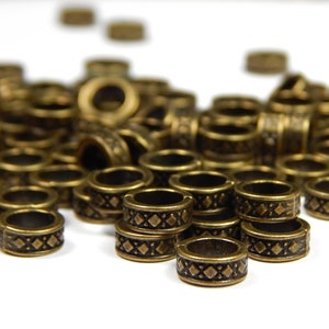 以下が含まれることがあります： ダイヤモンド模様の金色の金属ビーズの山。ビーズは小さく丸く、ランダムなパターンで配置されています。