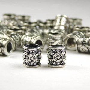 May include: Two silver metal beads with an intricate Celtic knot design. The beads are round and have a smooth, polished finish.