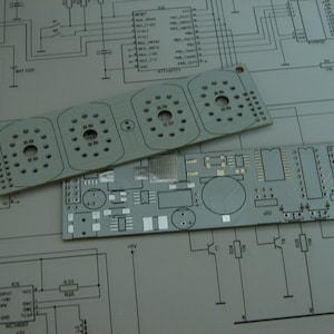Może przedstawiać: Dwie płytki drukowane, jedna z trzema okrągłymi komponentami, a druga z różnymi komponentami, umieszczone na schemacie obwodu drukowanego.