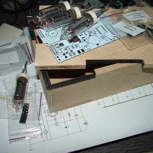 Könnte beinhalten: Eine Holzkiste mit einer Platine, Vakuumröhren und verschiedenen elektronischen Bauteilen. Die Kiste ist geöffnet und die Bauteile sind sichtbar. Es gibt auch mehrere kleine Beutel mit elektronischen Teilen.