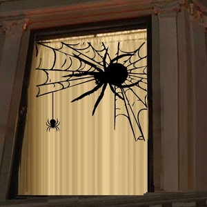 Peut inclure: Un autocollant de toile d'araignée noire avec une grosse araignée au centre. La toile est fixée à une fenêtre avec un rideau transparent. Une petite araignée pend à un brin de toile.