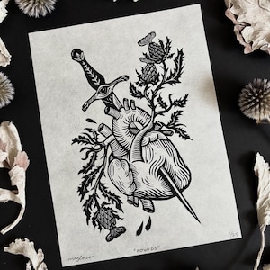May include: Black and white woodcut print of a heart pierced by a sword with a single eye on the blade. The heart is surrounded by thorny plants with flowers. The print is titled "Wounds" and numbered 1/25.