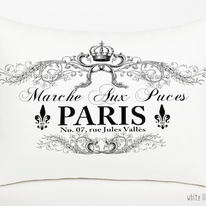 K&ouml;nnte beinhalten: Ein wei&szlig;es Leinenkissen mit einem schwarz-wei&szlig;en grafischen Design mit einer Krone, floralen Akzenten und dem Text "Marche Aux Puces PARIS No. 07, rue Jules Vall&egrave;s".