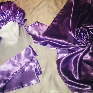 May include: A set of three purple satin hair accessories, including a bonnet, a scarf, and a headband. The satin is smooth and shiny.