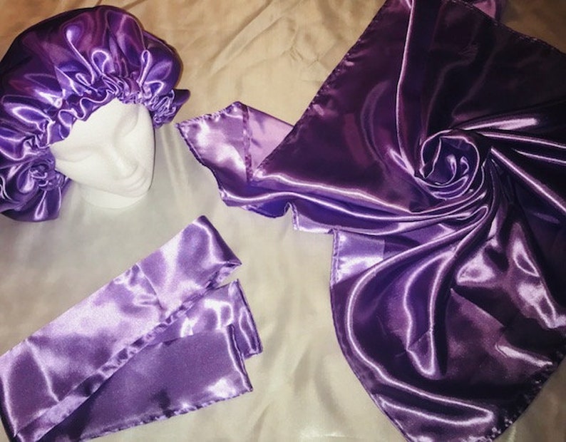 May include: A set of three purple satin hair accessories, including a bonnet, a scarf, and a headband. The satin is smooth and shiny.