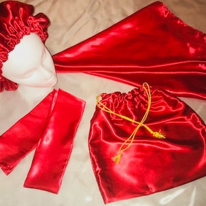 May include: A set of four red satin accessories, including a hair bonnet, a sleep mask, a drawstring bag, and a pair of eye masks.