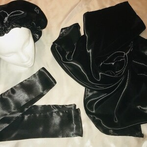 May include: A set of three black satin hair accessories. The set includes a satin bonnet, a satin scarf, and a satin headband.