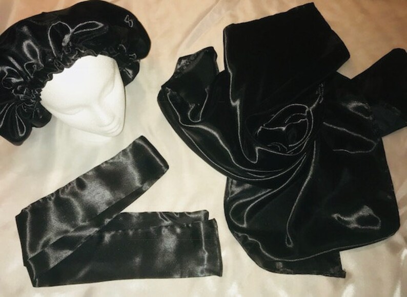 May include: A set of three black satin hair accessories. The set includes a satin bonnet, a satin scarf, and a satin headband.