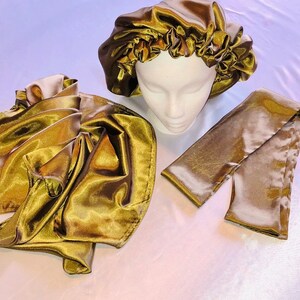 May include: A set of three gold satin hair accessories. The set includes a satin bonnet, a satin scarf, and a satin hair tie.
