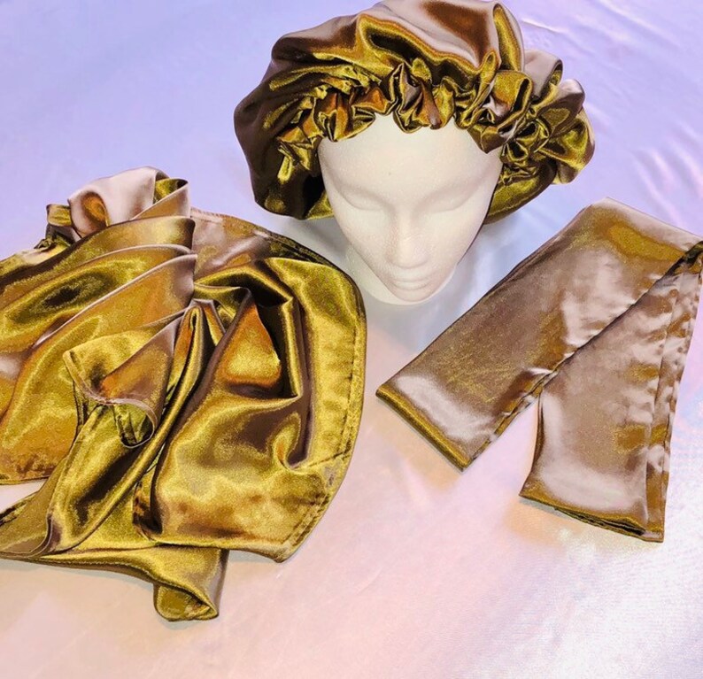 May include: A set of three gold satin hair accessories. The set includes a satin bonnet, a satin scarf, and a satin hair tie.