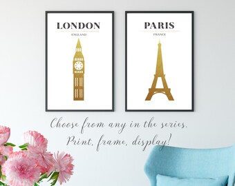 Può includere: Due stampe da parete incorniciate con sagome dorate del Big Ben a Londra, Inghilterra, e della Torre Eiffel a Parigi, Francia. Ogni stampa ha uno sfondo bianco con testo nero che identifica la città e il paese sopra il monumento dorato.