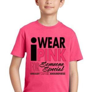 May include: A pink t-shirt with a black graphic that says "I Wear Pink For Someone Special" and "Breast Cancer Awareness".