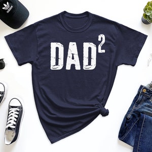 May include: A navy blue t-shirt with the text "DAD²" in white distressed lettering.