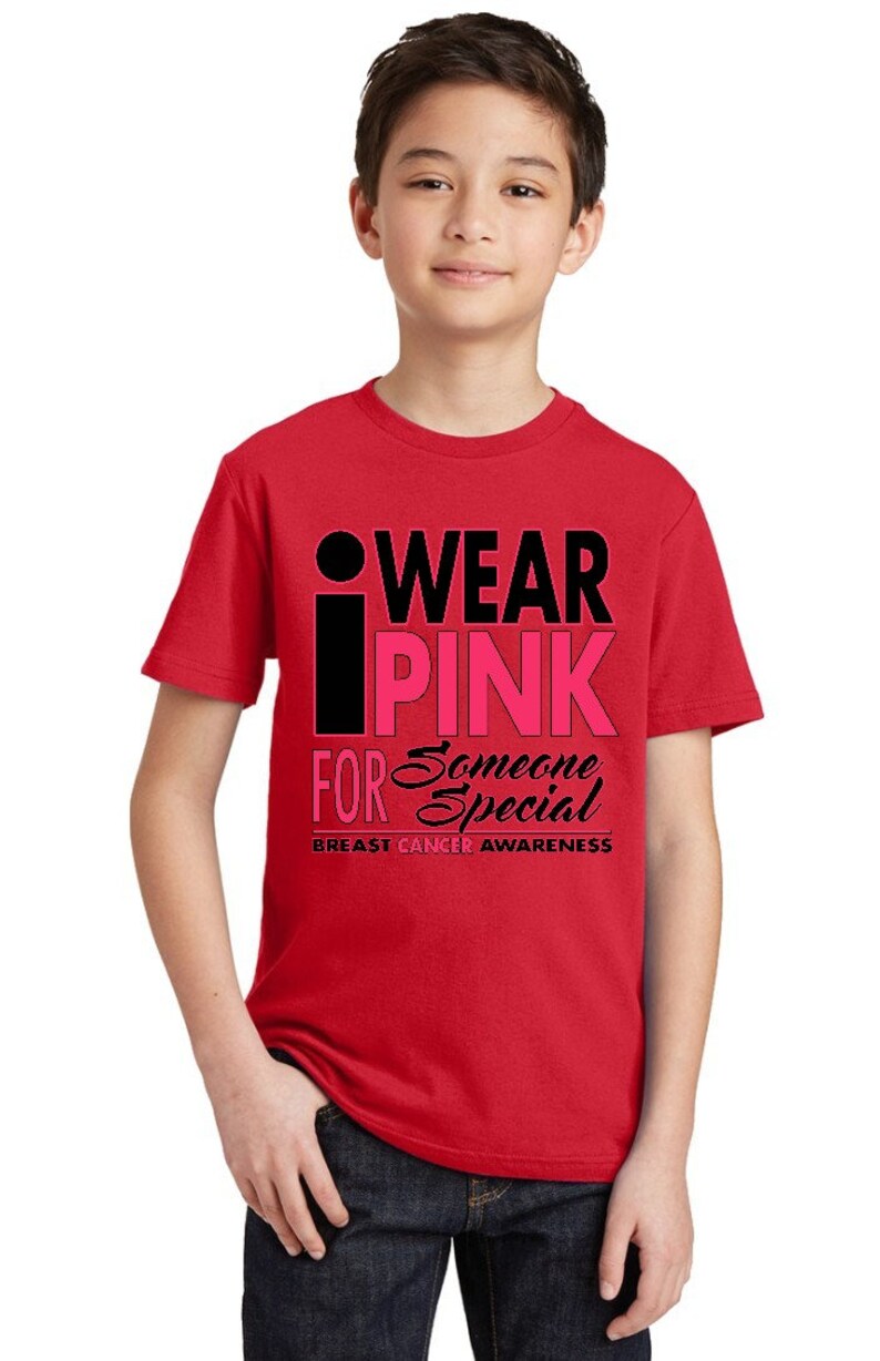 May include: Red t-shirt with a black and pink graphic that says "I Wear Pink For Someone Special" and "Breast Cancer Awareness".