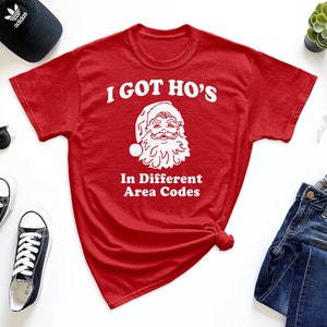 May include: Red t-shirt with a white graphic of Santa Claus and the text "I got ho's in different area codes".
