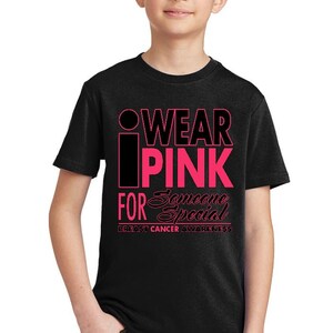 May include: Black t-shirt with pink lettering that reads "I Wear Pink For Someone Special" and "Breast Cancer Awareness".
