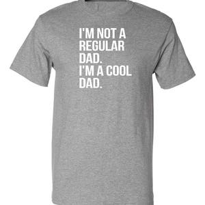 May include: A heather grey t-shirt with the text "I'm not a regular dad. I'm a cool dad."