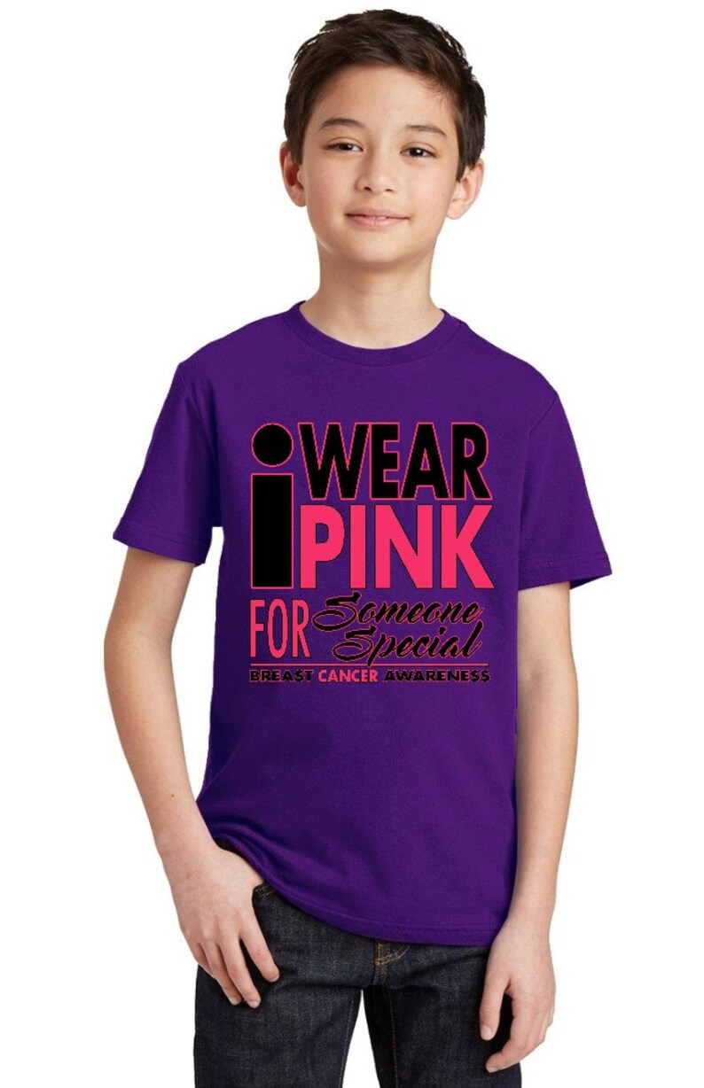May include: Purple t-shirt with a black and pink graphic that says "I Wear Pink For Someone Special" and "Breast Cancer Awareness".
