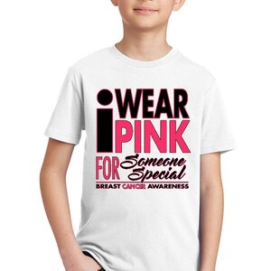 May include: White t-shirt with a pink and black graphic that says "I Wear Pink For Someone Special" and "Breast Cancer Awareness".