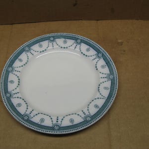 Puede incluir: Un plato de cerámica blanco con un diseño floral azul y blanco alrededor del borde.