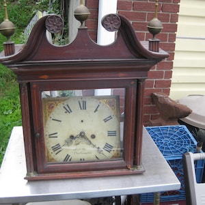 May include: Antique wooden clock with a glass face and a Roman numeral clock face. The clock face reads "John M.  Oughton,  Clockmaker".