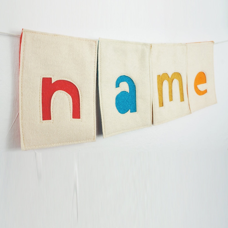 May include: A felt banner with the word "name" spelled out in colorful letters. The letters are red, blue, yellow, and orange.