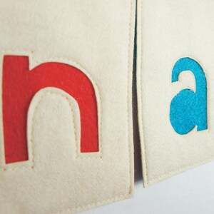 May include: Two felt squares with the letters "n" and "a" cut out. The "n" is red and the "a" is blue.