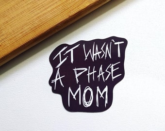 May include: Black and white sticker with the text "IT WASN'T A PHASE MOM" in a handwritten style.