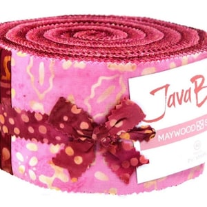 May include: A rolled bundle of fabric strips featuring a pink and gold batik pattern, secured with a dark red polka dot ribbon. A white paper label is wrapped around the side, displaying the text Java B and MAYWOOD STUDIO in black and red.