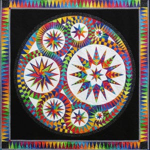 May include: A colorful quilt with a black background, featuring a central circular design with white circles and vibrant star patterns in shades of red, orange, yellow, green, blue, and purple. The border is a repeating triangle pattern.
