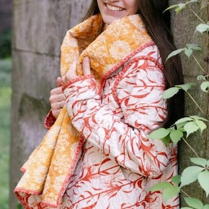 May include: A quilted jacket with a white background and a red floral pattern. The jacket has a yellow collar and trim. The jacket is worn with a matching scarf. The jacket is a unique piece of clothing.