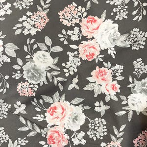May include: A black fabric with a white and pink floral pattern. The flowers are stylized and have a watercolor effect.
