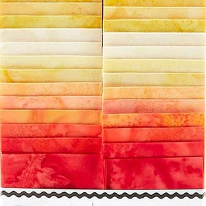May include: A stack of fabric strips in shades of orange, yellow, and red. The fabric strips are 2 1/2" wide and come in 40 pieces with 20 fabric designs. The label reads "Island Batik Opulent Orange Batiks."