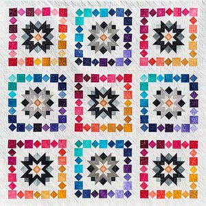 May include: A handmade quilt with a repeating star pattern. Each star is surrounded by a square frame of colorful squares and diamonds. The quilt features a palette of black, gray, and white, with accents of pink, blue, and yellow.