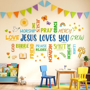 May include: A wall decorated with colorful text and graphics, including the words "Jesus Loves You," a cross, a rainbow, and a butterfly. Two small chairs, one blue and one yellow, sit near a small table. A bookshelf with children's books is visible.