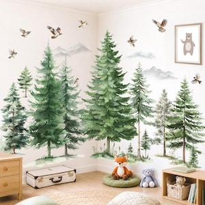 May include: A wall decal set featuring watercolor-style green pine trees, gray mountain silhouettes, and various birds in flight. The design includes a framed print of a brown bear and is displayed on a white wall above a wooden floor.