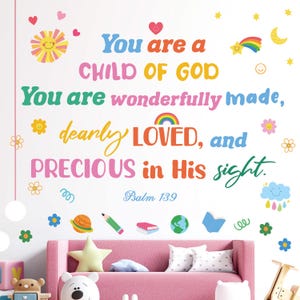 Puede incluir: Un vinilo decorativo con texto colorido que dice "You are a CHILD OF GOD, You are wonderfully made, dearly LOVED, and PRECIOUS in His sight." Elementos decorativos incluyen corazones, estrellas, flores y un arcoíris. Un sofá rosa está debajo.