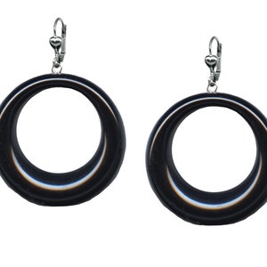 May include: A pair of black hoop earrings with a silver clip-on closure. The earrings are made of a smooth, shiny material.