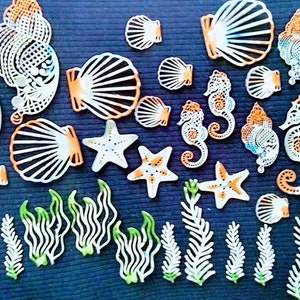 May include: A set of white and orange sea-themed decorations, including seahorses, seashells, starfish, and seaweed. The decorations are made of a delicate, lacy material.