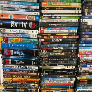 May include: A stack of DVDs featuring various titles, including "The Office", "Friends", "How I Met Your Mother", "Saving Private Ryan", "Snatch", "Michael Clayton", "Spider-Man", "Shrek", "Evan Almighty", "Eight Legged Freaks", "Escape from Hell", and "Ghouls on the Go".