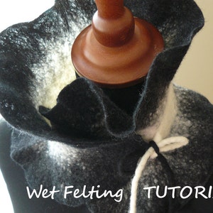 May include: A handmade felted cowl in black and white, draped over a mannequin head. The cowl has a ruffled edge and a tie closure. The text "Wet Felting TUTORIAL" is visible.