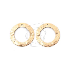 Puede incluir: Dos círculos de metal de color dorado con textura martillada y un agujero en la parte superior. Los círculos tienen un diámetro de aproximadamente 2,5 cm.