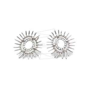 May include: A pair of silver earrings with a sunburst design. The earrings feature a circular shape with a smaller circle inside, surrounded by radiating points.