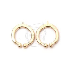 May include: Two gold-toned metal rings with a textured finish and rounded edges. The rings are open and have a slightly irregular shape.