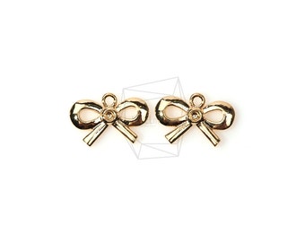 May include: Two gold-toned metal bow charms with a small rhinestone in the center of each bow.