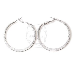 Könnte beinhalten: Ein Paar silberne Creolen mit einer strukturierten Oberfläche.