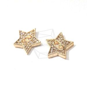 May include: Two gold-tone star-shaped charms with clear crystal embellishments. Each charm has two holes for attaching to jewelry or other crafts.